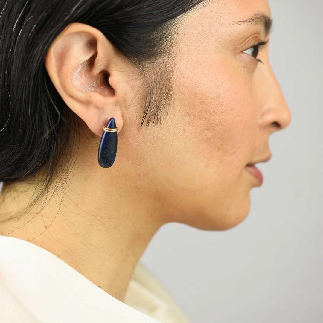 Close up image of a model wearing 14K gold fill Slender Lapis Drop Post Earrings from Zurina Ketola