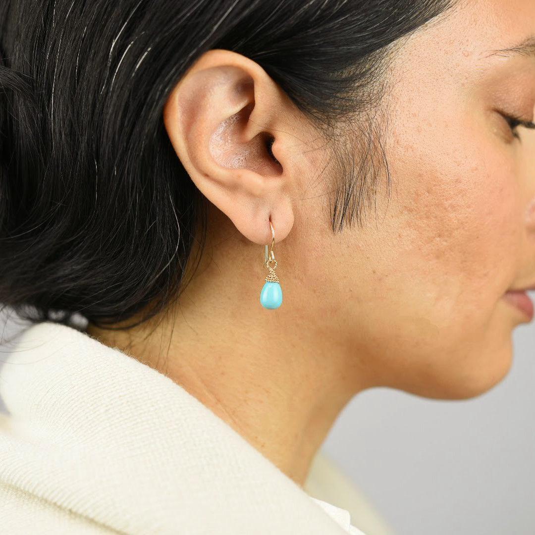 Close up image of a model wearing 14K gold fill Smooth Turquoise Drop Earrings from Zurina Ketola