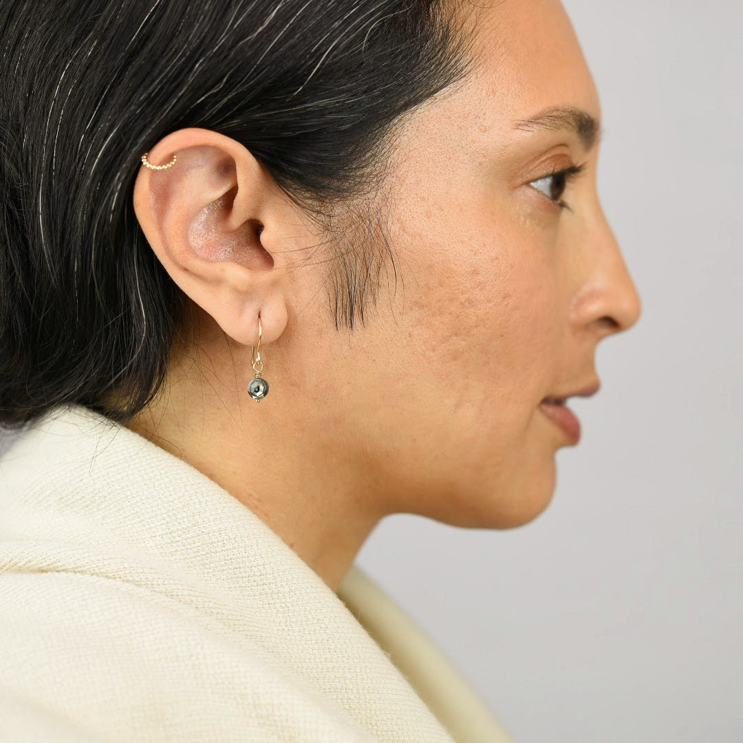 Close up image of a model wearing 14K gold filled Abalone Delicate Star Facet Earrings from Zurina Ketola