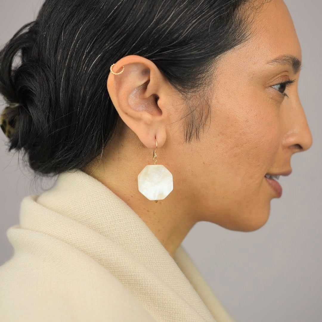Close up image of a model wearing 14K gold filled Kemyab Shell Hexagon Earrings from Zurina Ketola