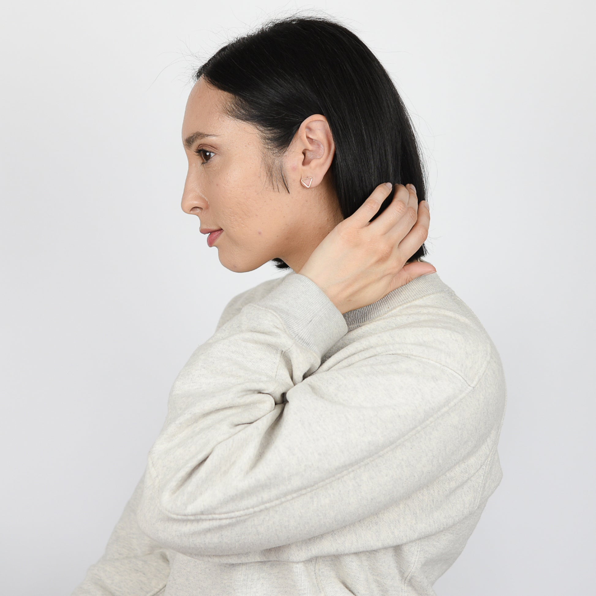 Model wearing triangle post earrings in 14K gold fill.