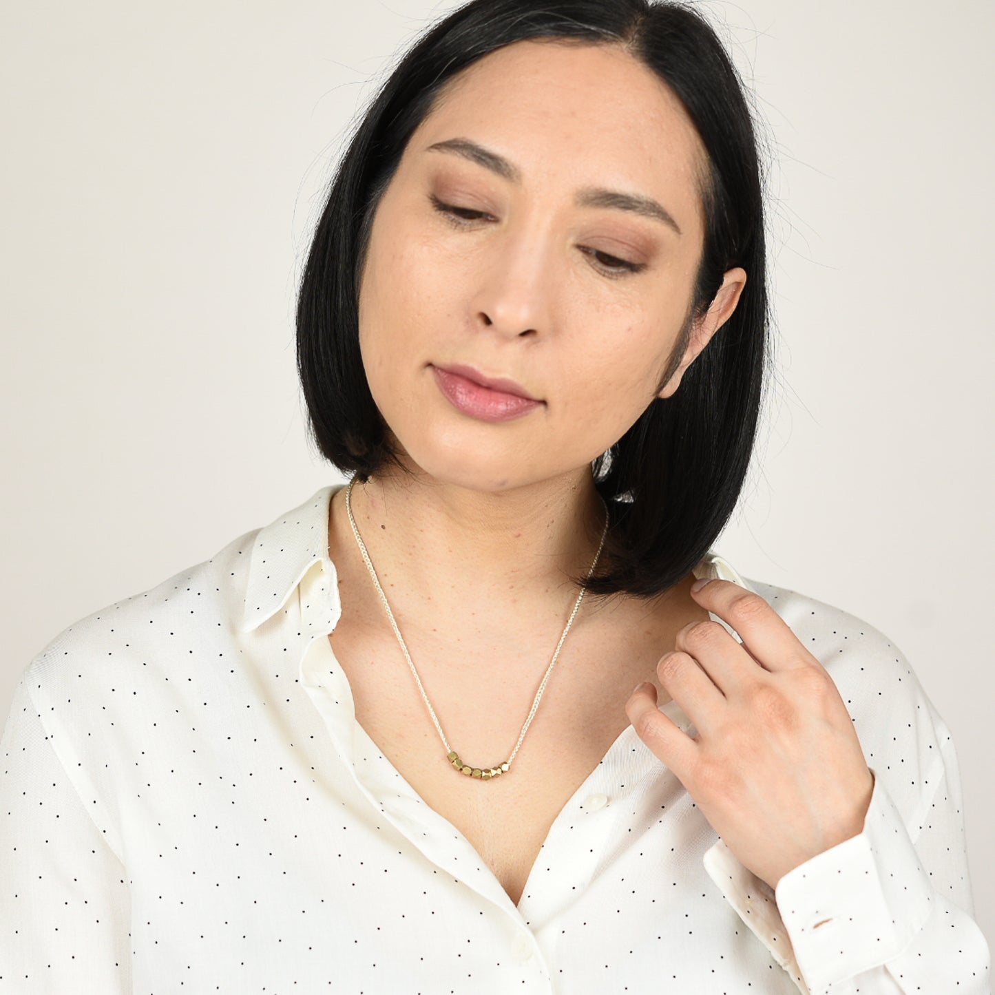 Headshot of model wearing white shirt with black dots wearing a silk abacus necklace.