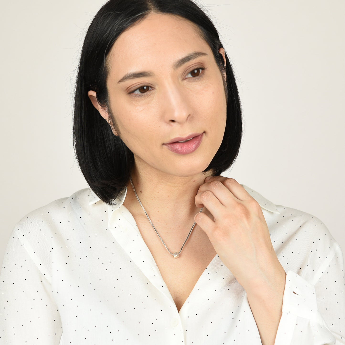 Model wearing ecru silk necklace with silver details.