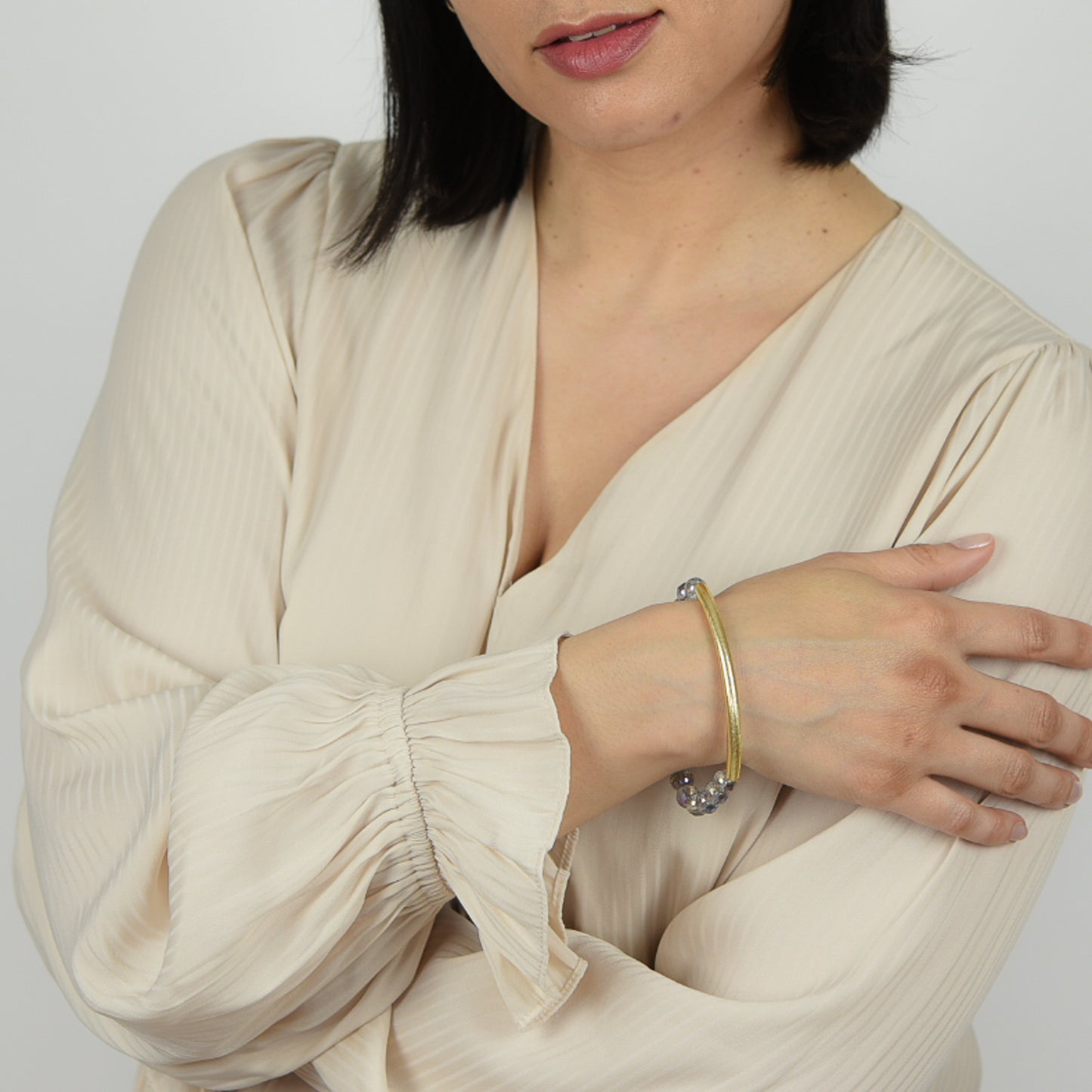 Model wearing gemstone bangle bracelet in mystic crystal with gold details.