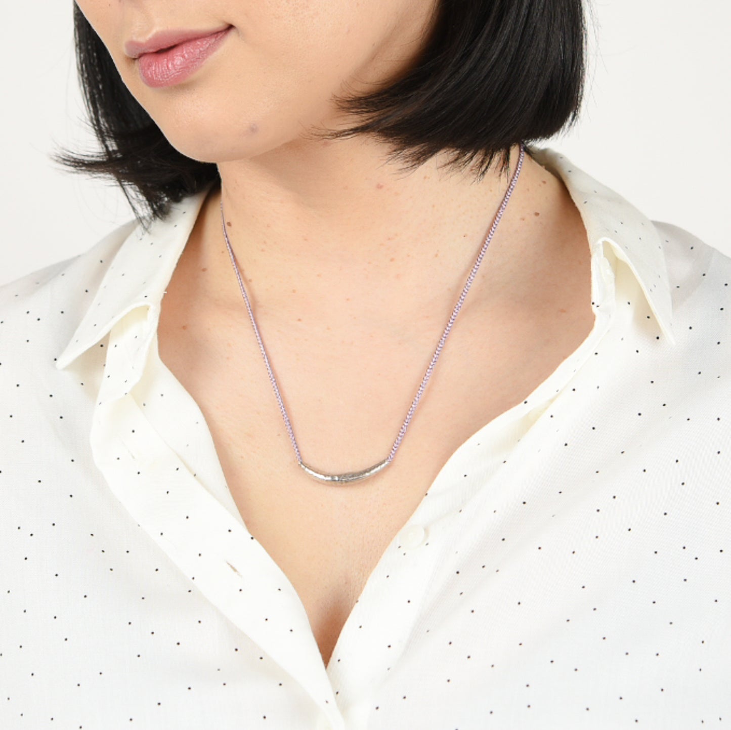 Model wearing slender crescent silk necklace.