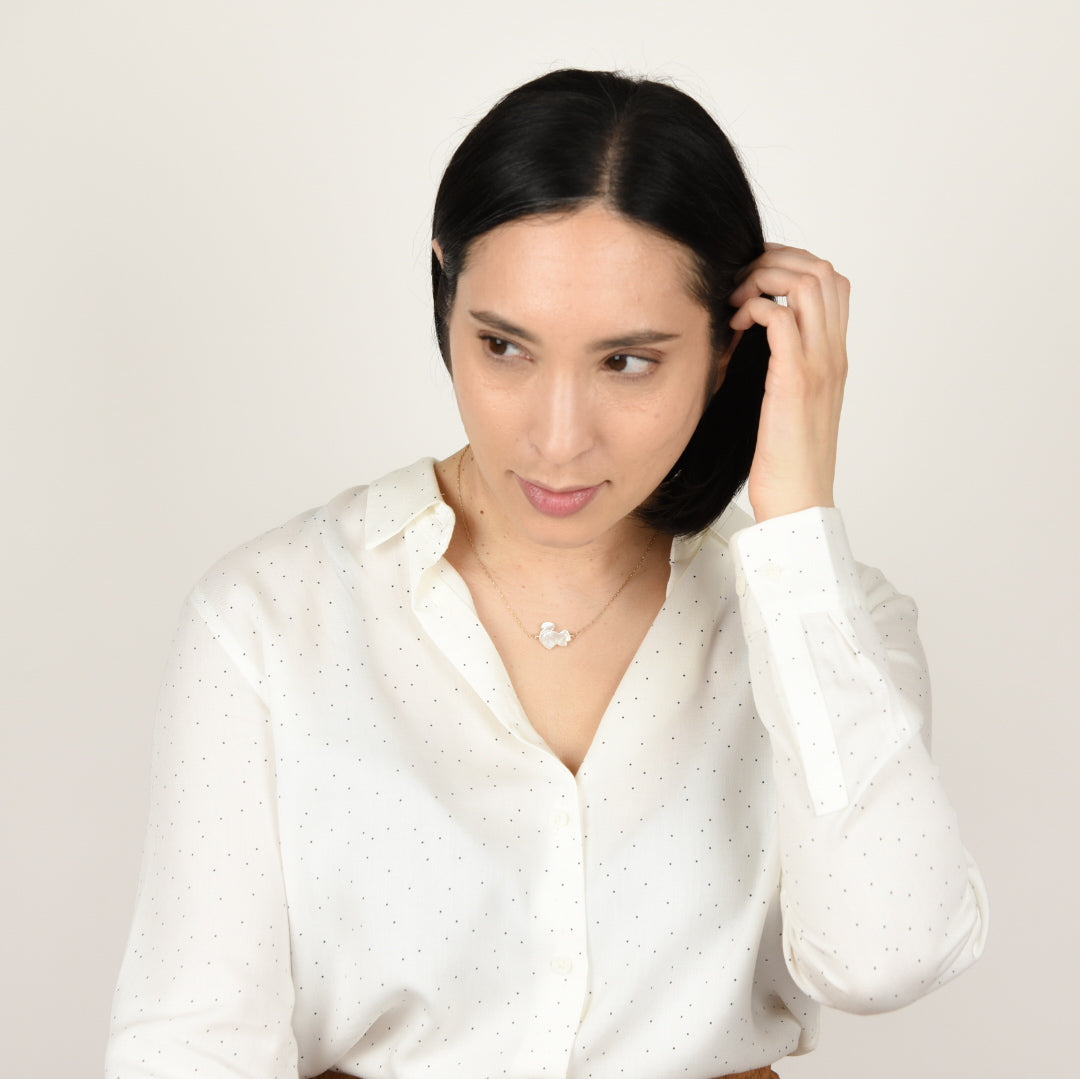 Model wearing mother of pearl squirrel necklace on gold.