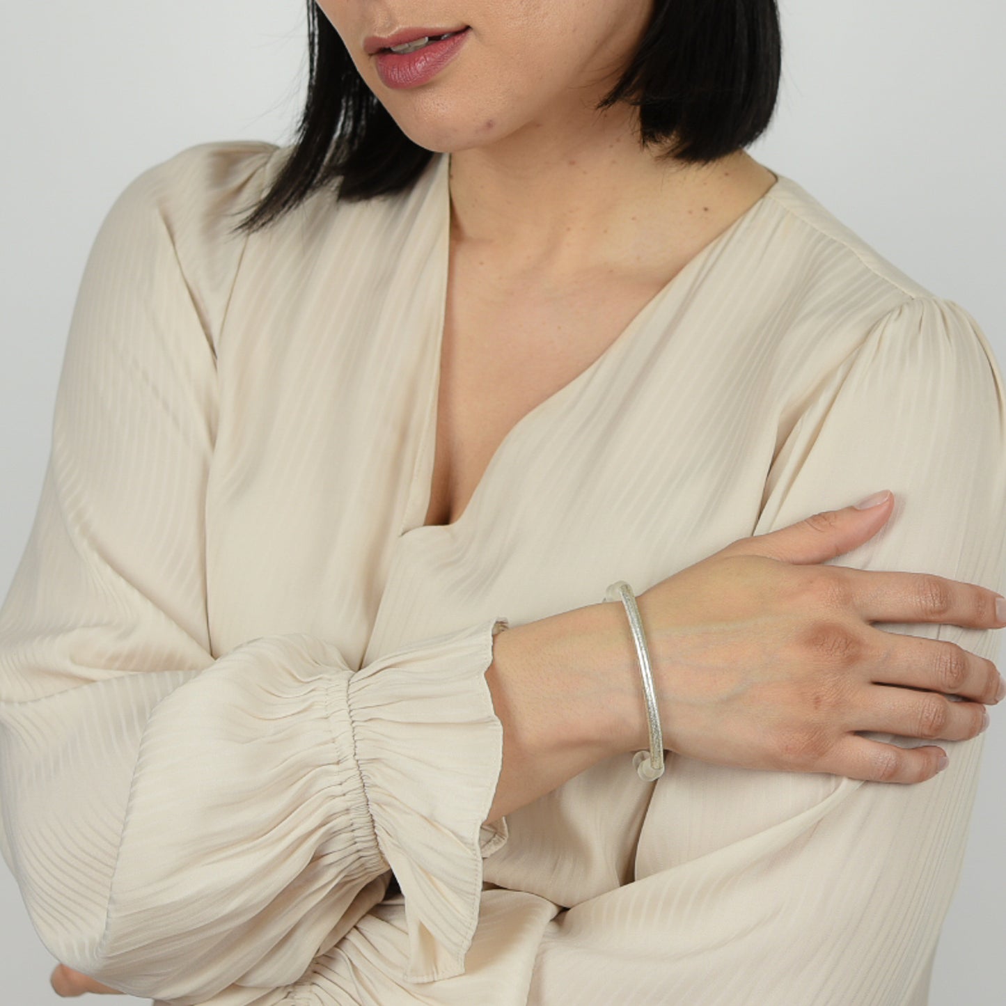 Model wearing gemstone bangle bracelet in crystal with silver details. 