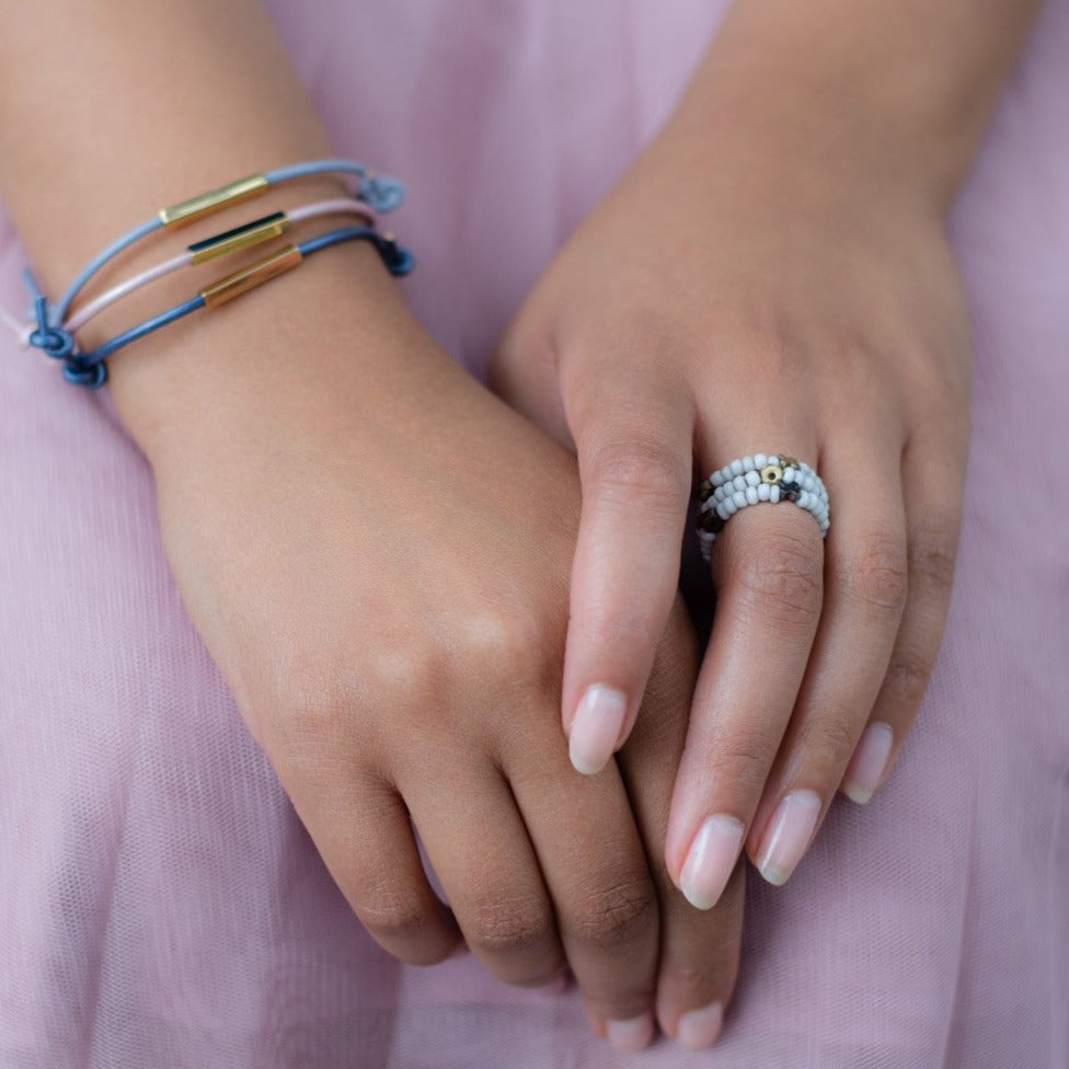 Close up of hands, model wearing leather bracelets and beaded stacking rings on pink tulle skirt
